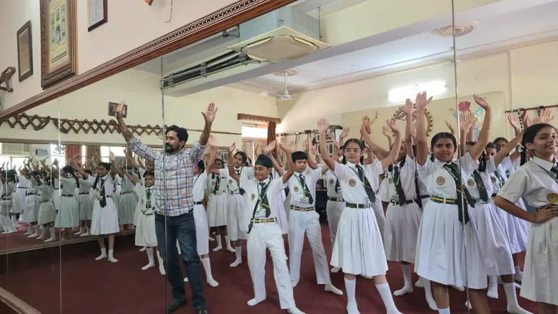 Students rehearsing dance steps with raised arms