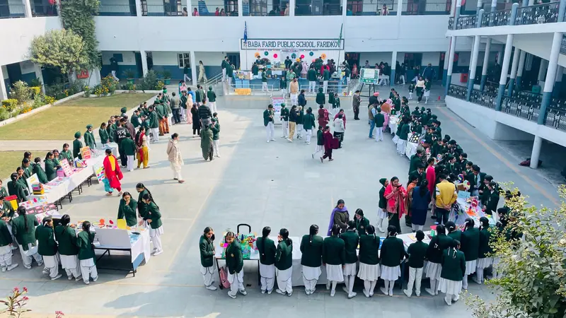 Students in green school blazers at a school exhibition in the campus courtyard